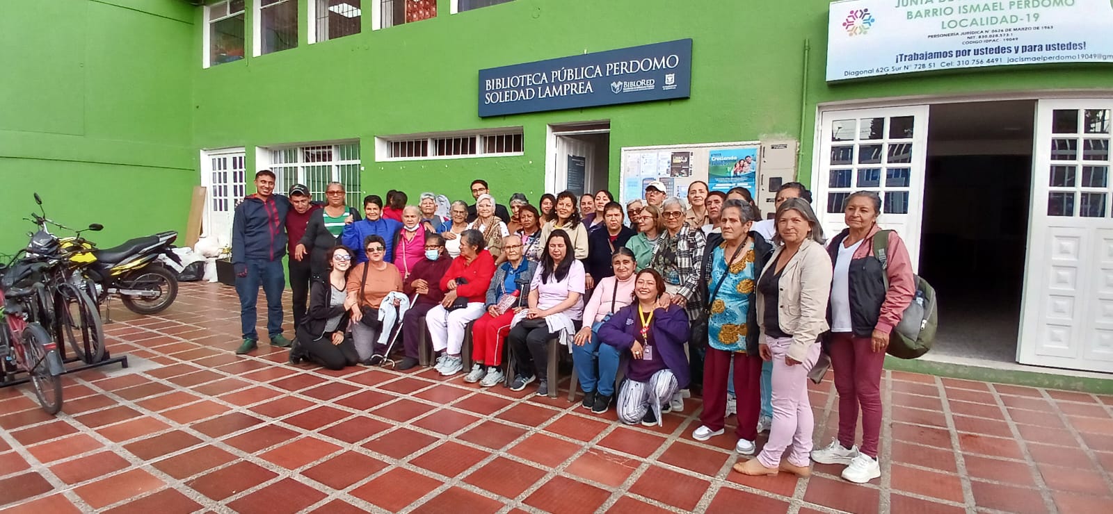 grupo de adultos mayores posando frente a la fachada de la biblioteca Perdomo