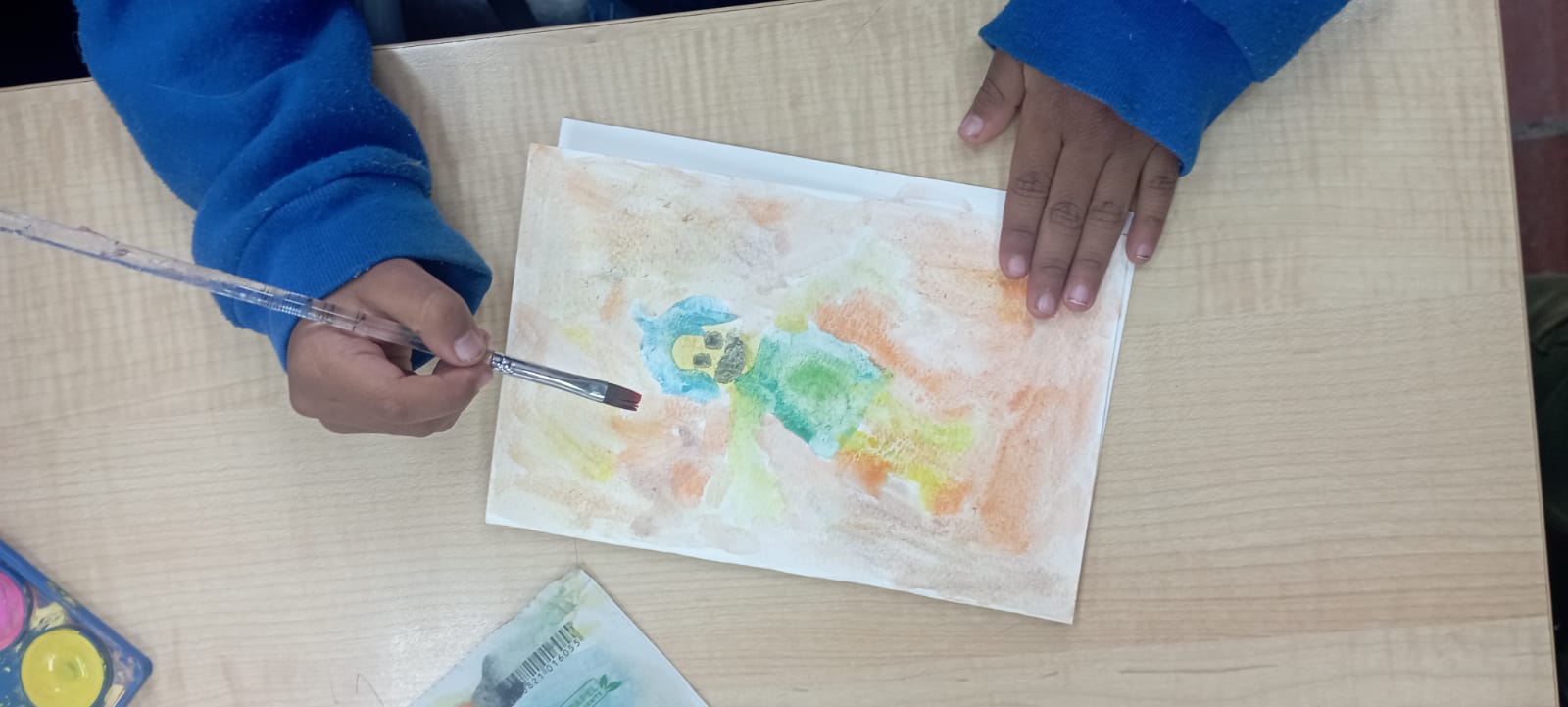 Niño pintando en hoja de papel en la sala infantil de la biblioteca