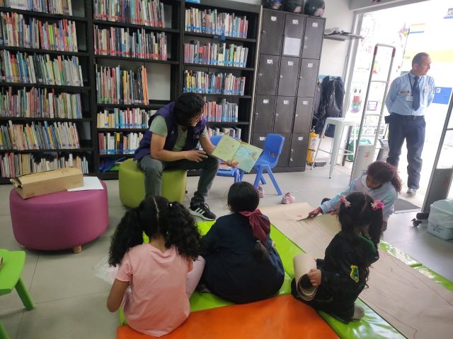 grupo de niños escuchando la lectura en voz alta que realiza la docente