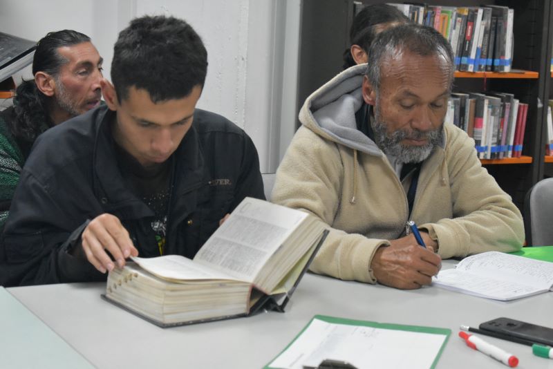 un jóven y un adulto mayor leyendo juntos