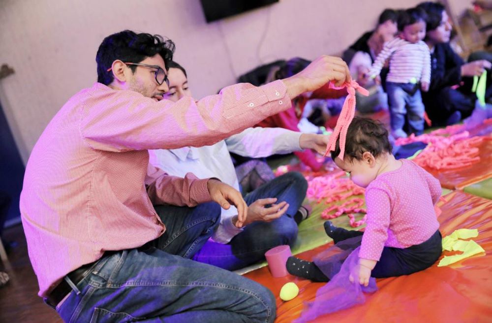 Cuidadores junto a sus bebés participando en actividades sensoriales y lúdicas en la biblioteca