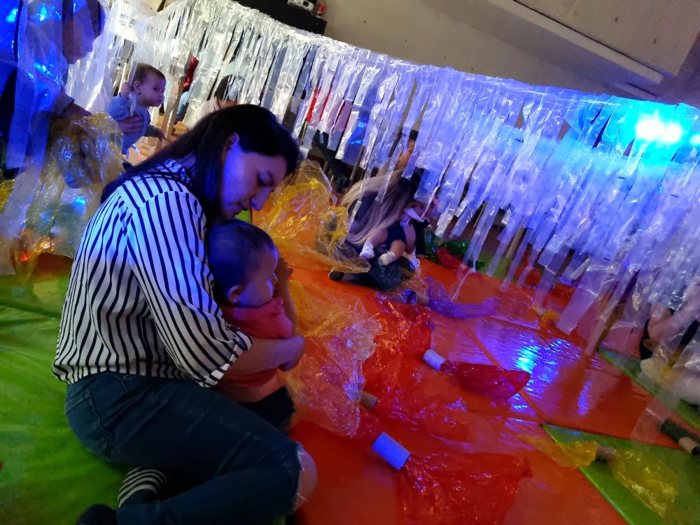 Cuidadores junto a sus bebés participando en actividades sensoriales y lúdicas en la biblioteca