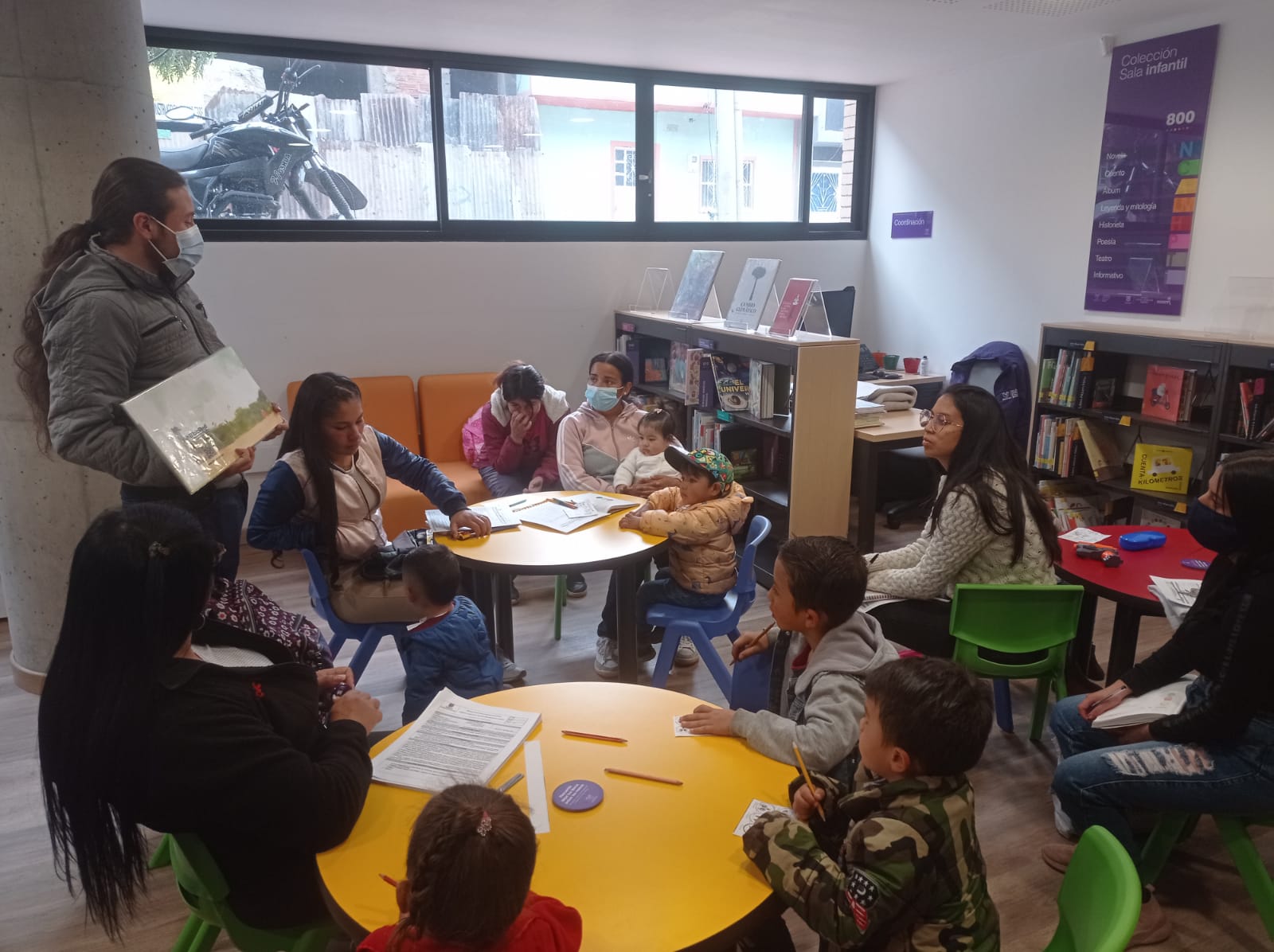 grupo de niños y niñas prestando atención a la lectura de un libro por parte del docente