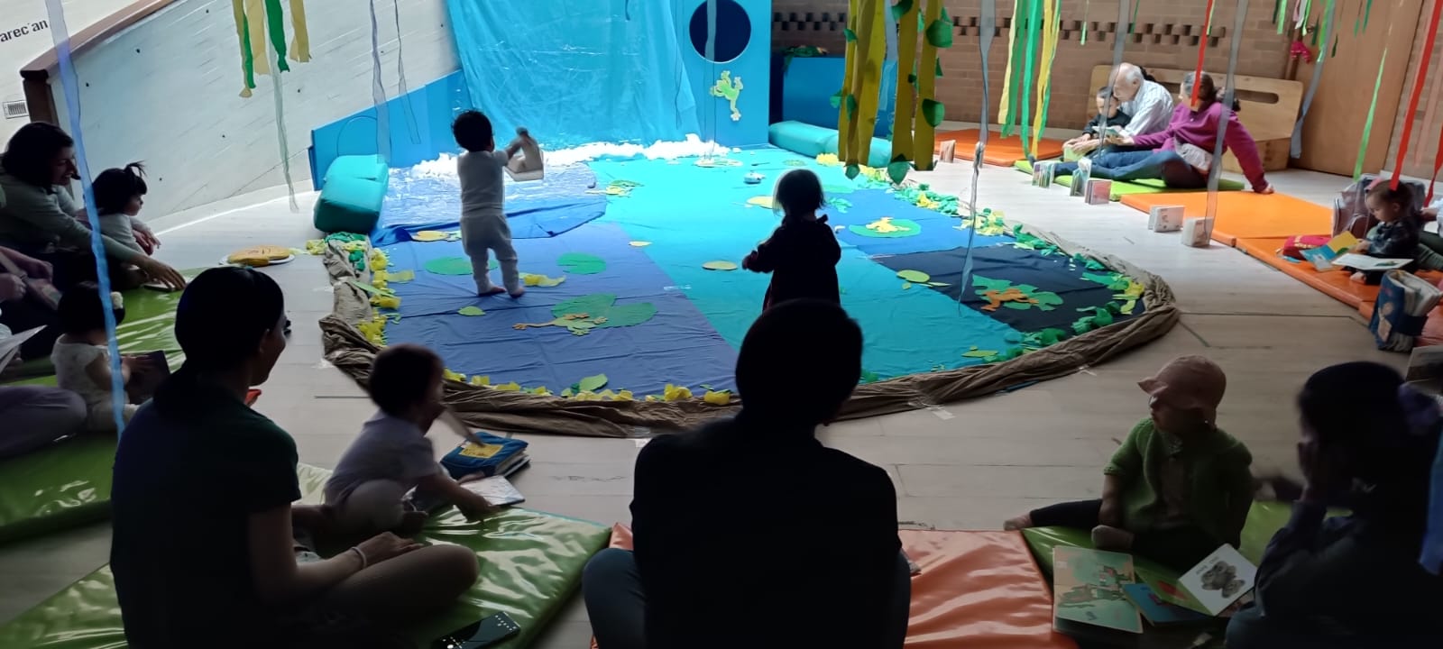 grupo de bebés jugando en medio de un escenario con luces color azul 